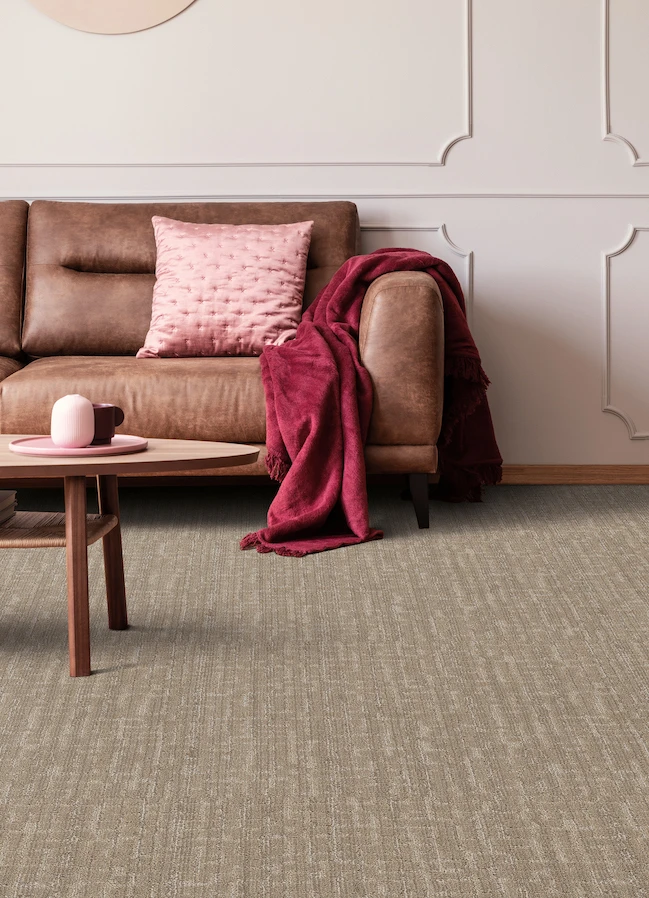 textured brown carpets in a living room with brown leather couch and pink accents